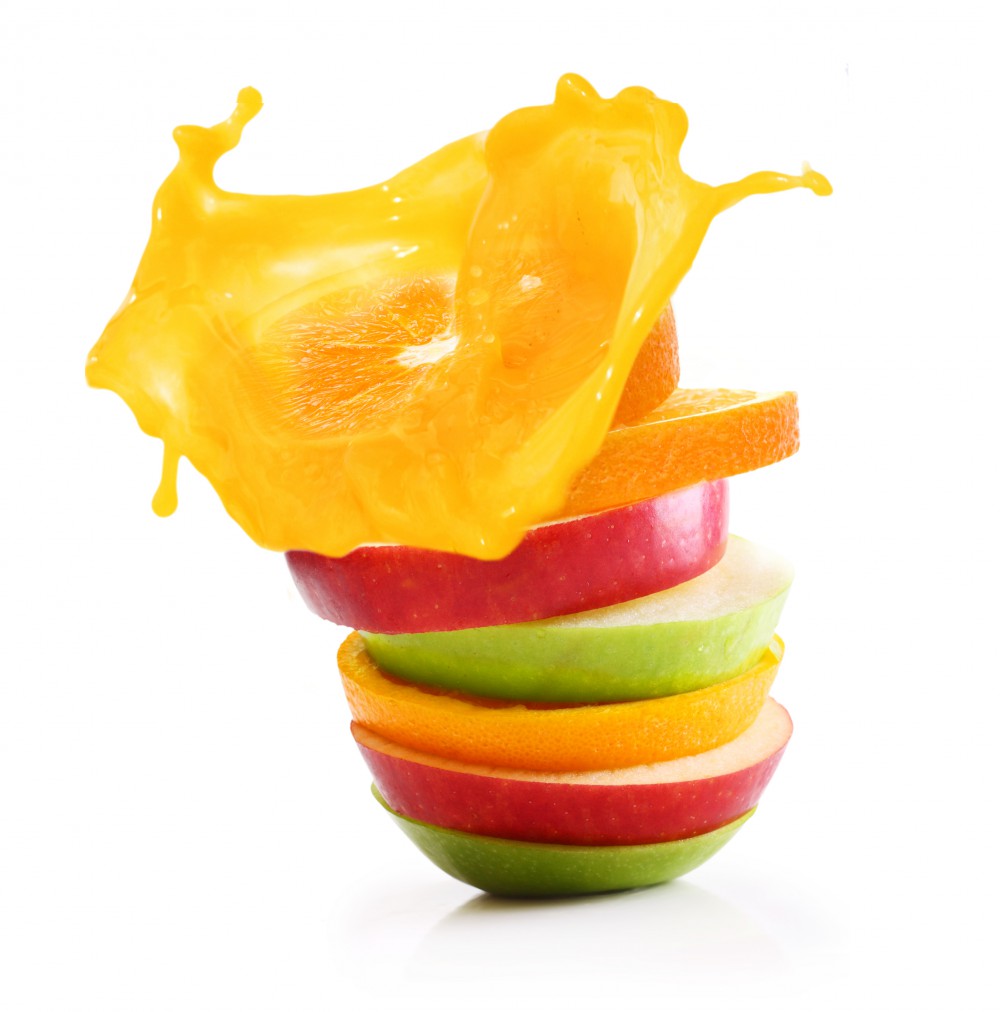 Stack of orange fruit and apples slices with juice splash.